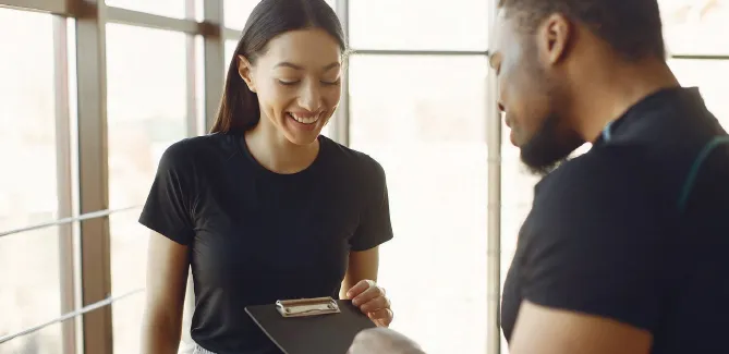 A trainer reviewing a plan on a clipboard with a new member
