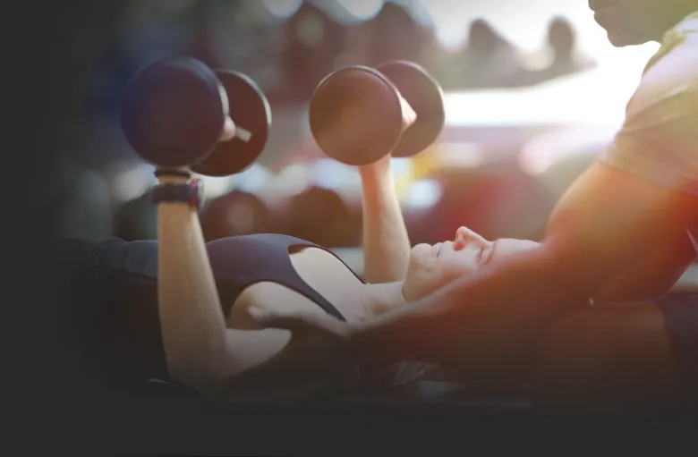 A ZUM trainer spotting a member during a dumbbell chest press