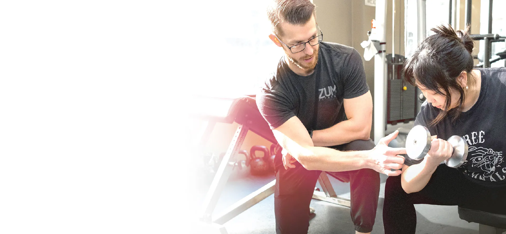 ZUM trainer guiding a member through a dumbbell curl